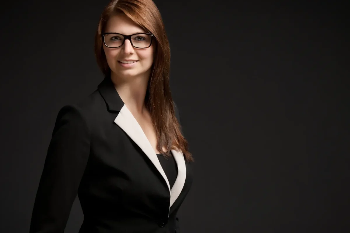 Porträtfoto einer jungen Frau im Business-Outfit vor neutralem Hintergrund, freundlich lächelnd – ideal für Bewerbungen.