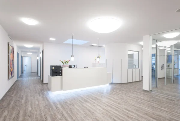 Moderner Eingangsbereich einer Zahnarztpraxis mit Theke, Wartebereich und Behandlungszimmer im Hintergrund