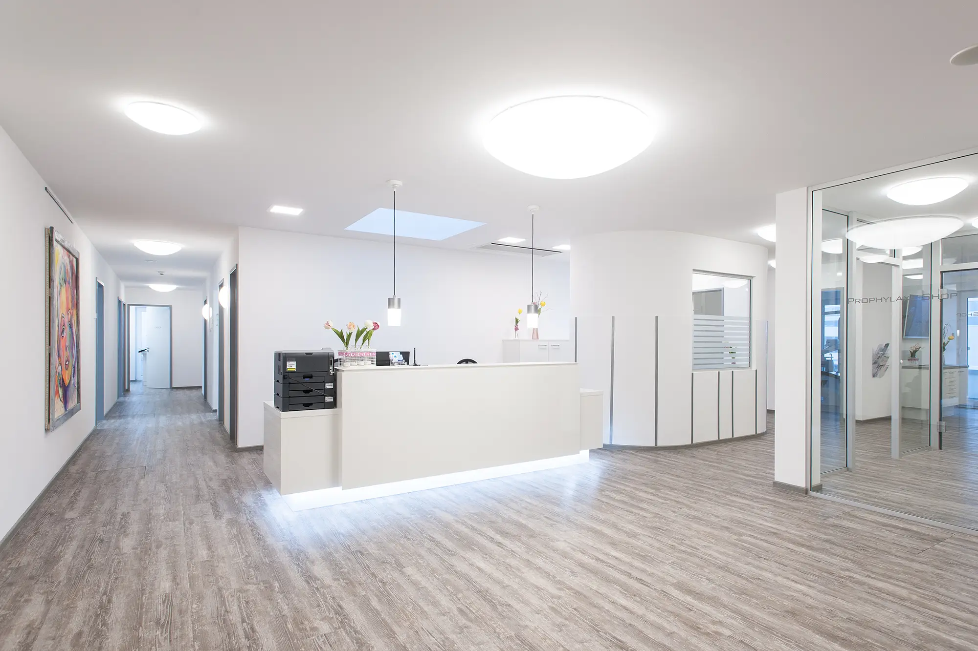 Moderner Eingangsbereich einer Zahnarztpraxis mit Theke, Wartebereich und Behandlungszimmer im Hintergrund