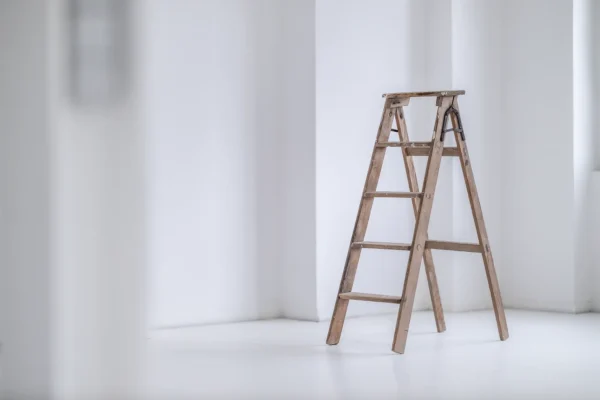 Holzleiter als Requisite in weißem Tageslichtstudio vor einer Wandnische mit Licht und Schatten